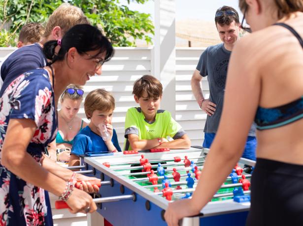 People playing table football outdoors on a sunny day.