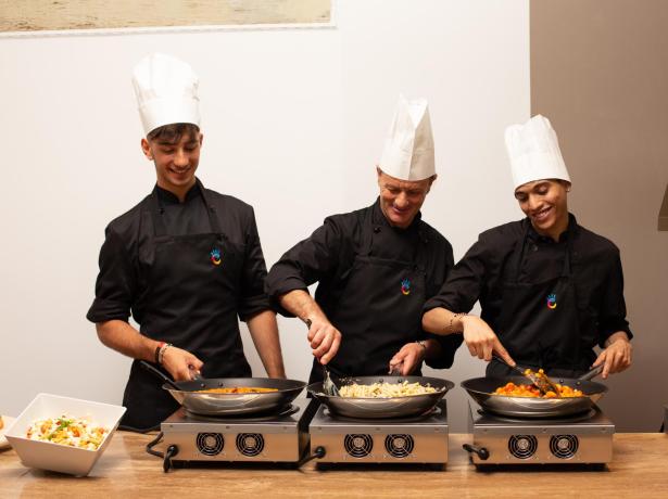 Tre chef cucinano piatti deliziosi su fornelli.