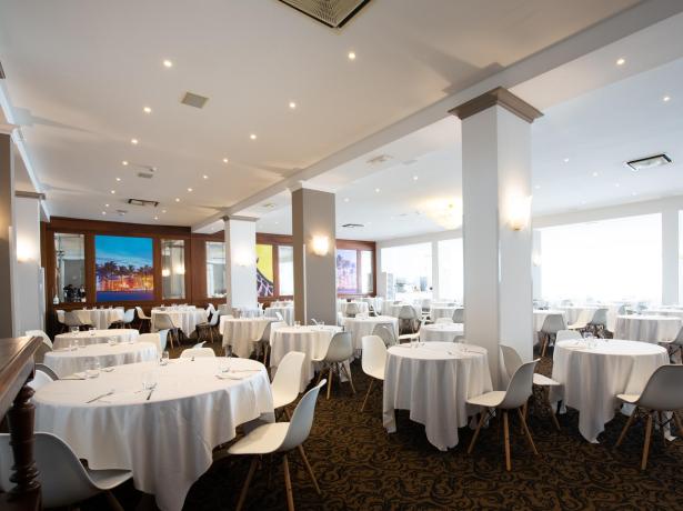 Elegante sala da pranzo con tavoli rotondi e sedie bianche.
