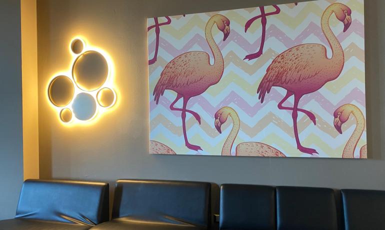 Sala con divano nero, lampada circolare e quadro di fenicotteri.