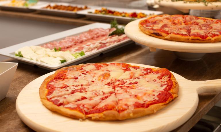 Pizze e salumi su un tavolo da buffet.