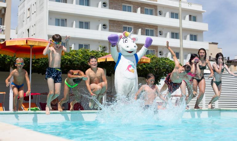 Bambini e mascotte saltano in piscina.