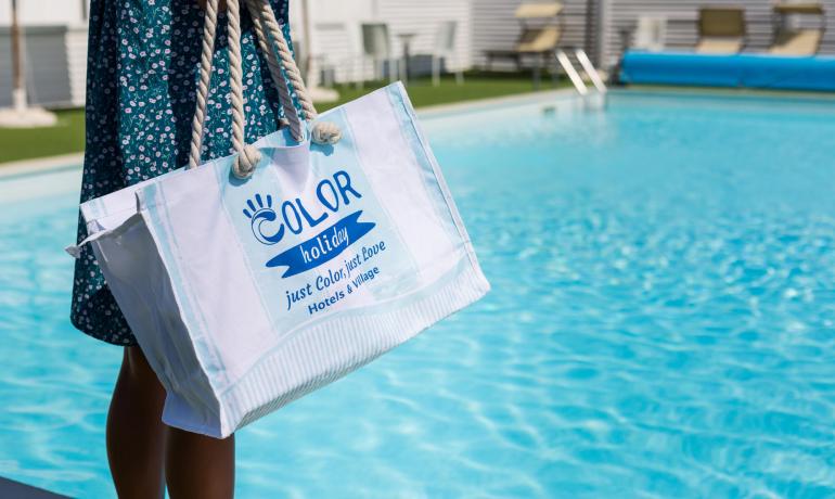 Borsa estiva colorata vicino a una piscina scintillante, atmosfera di vacanza e relax.