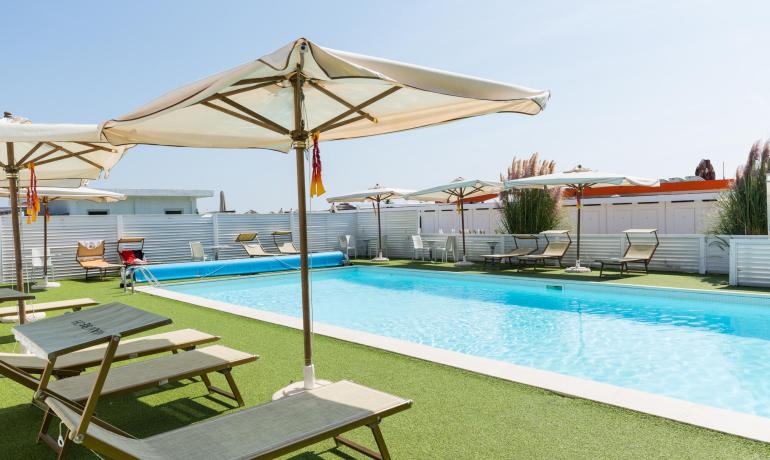 Piscina all'aperto con lettini e ombrelloni, ambiente rilassante.