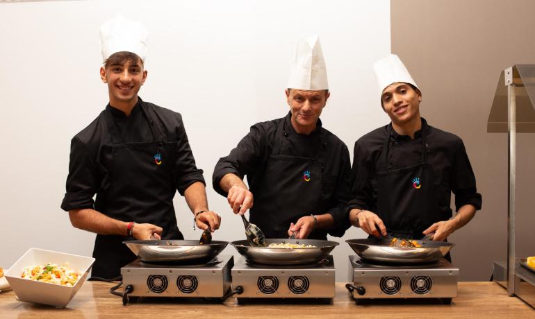 Drei lächelnde Köche kochen zusammen in der Küche.