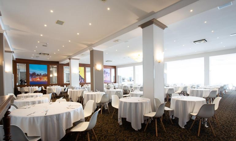 Elegant dining room with round tables and white chairs.