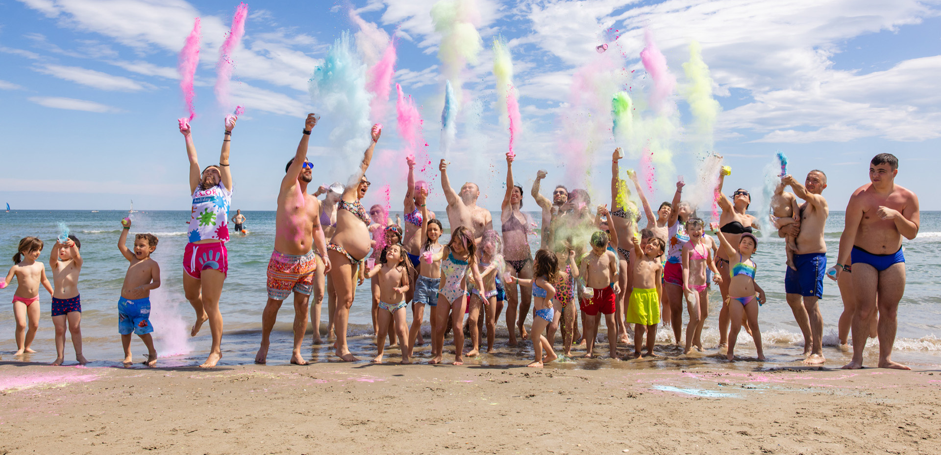 Papà e figlia sorridenti giocano sulla spiaggia con secchiello e paletta.