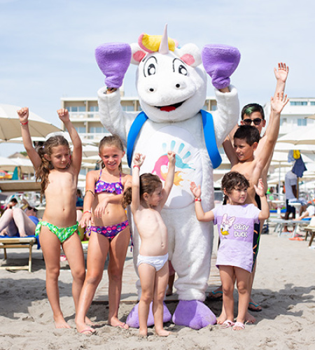 Happy children on the beach with a colorful unicorn costume.