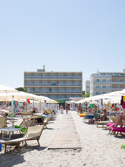 Crowded beach, colorful umbrellas, bright sun, lively and joyful summer.