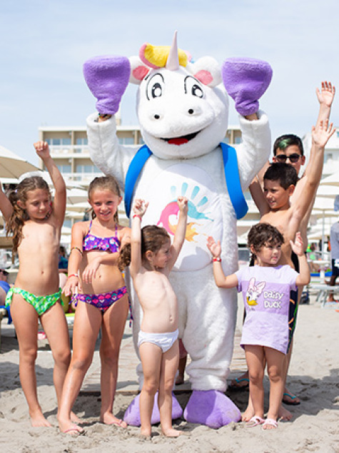 Happy children on the beach with a colorful unicorn costume.