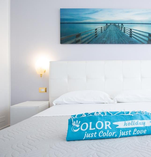 Bright, relaxing room with white bed and photo of a pier over the sea.