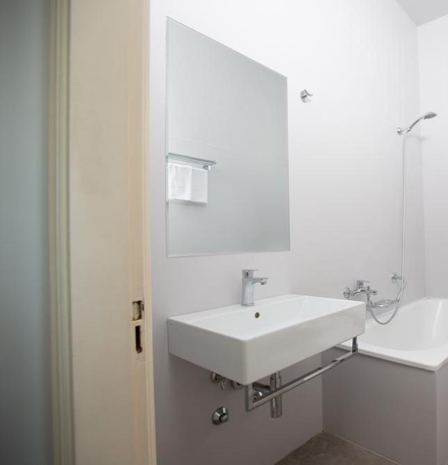 Modern, minimalist, and bright bathroom with a bathtub and large mirror.